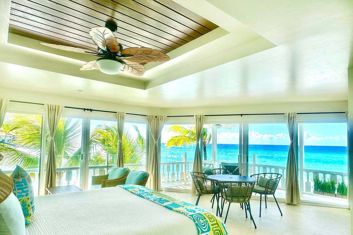 A spacious bedroom with a large bed, a ceiling fan, and a view of the ocean.