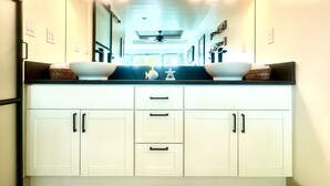 Una cocina moderna con armarios blancos, encimeras negras y un lavamanos doble de gran capacidad.