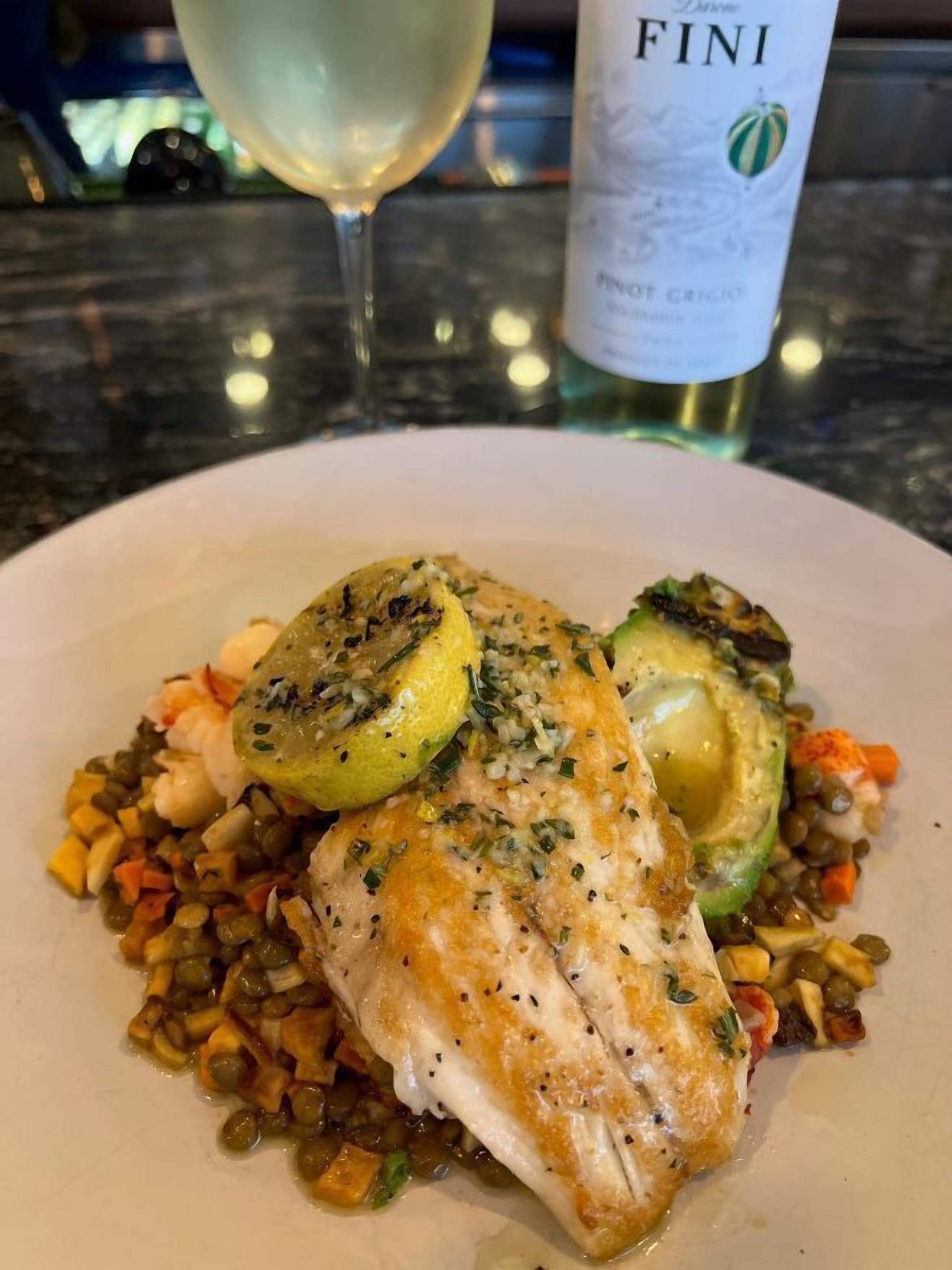 Een bord eten met een fles Fini wijn en een glas witte wijn op de achtergrond.