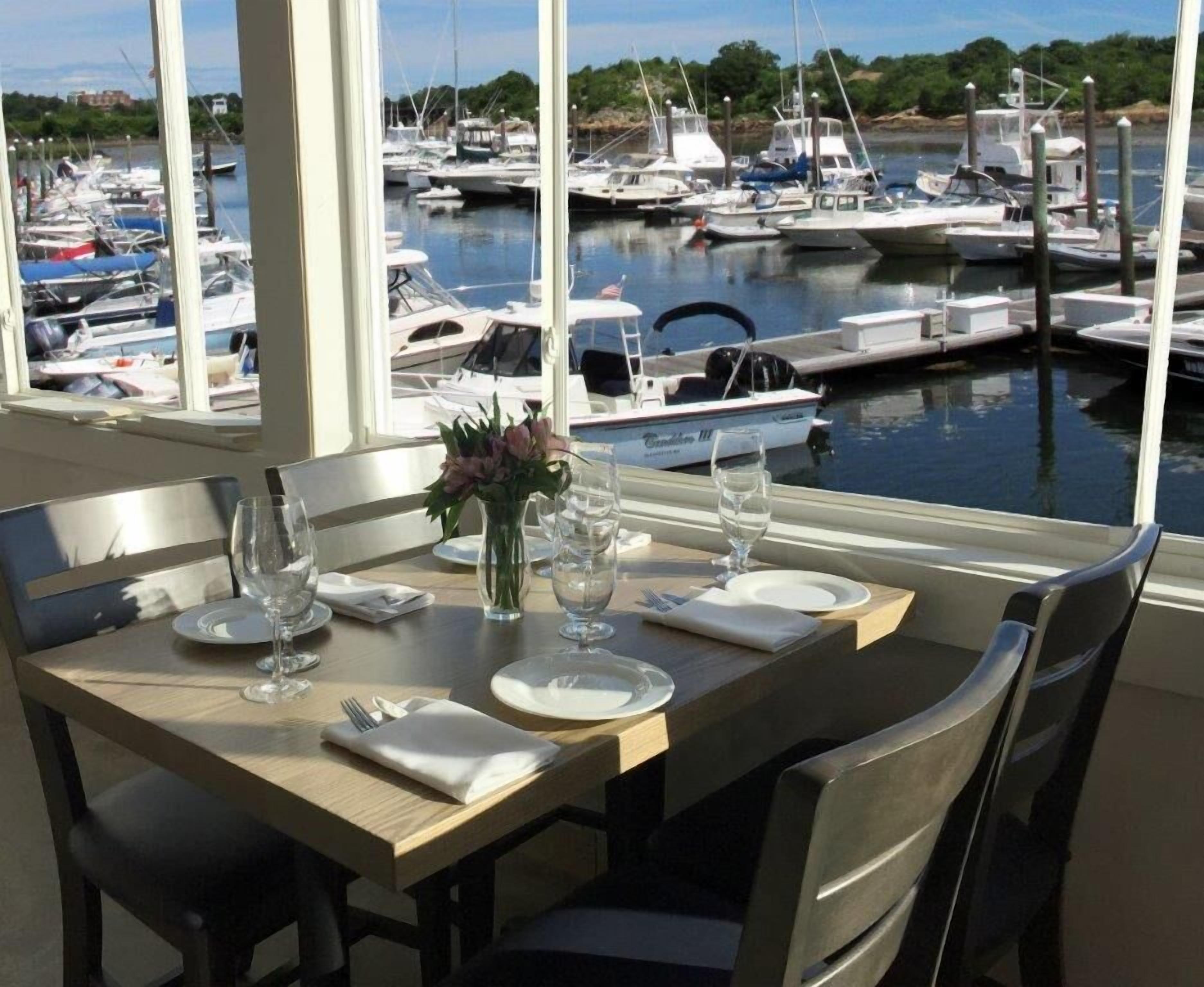 A dining table set for two with a view of a marina.