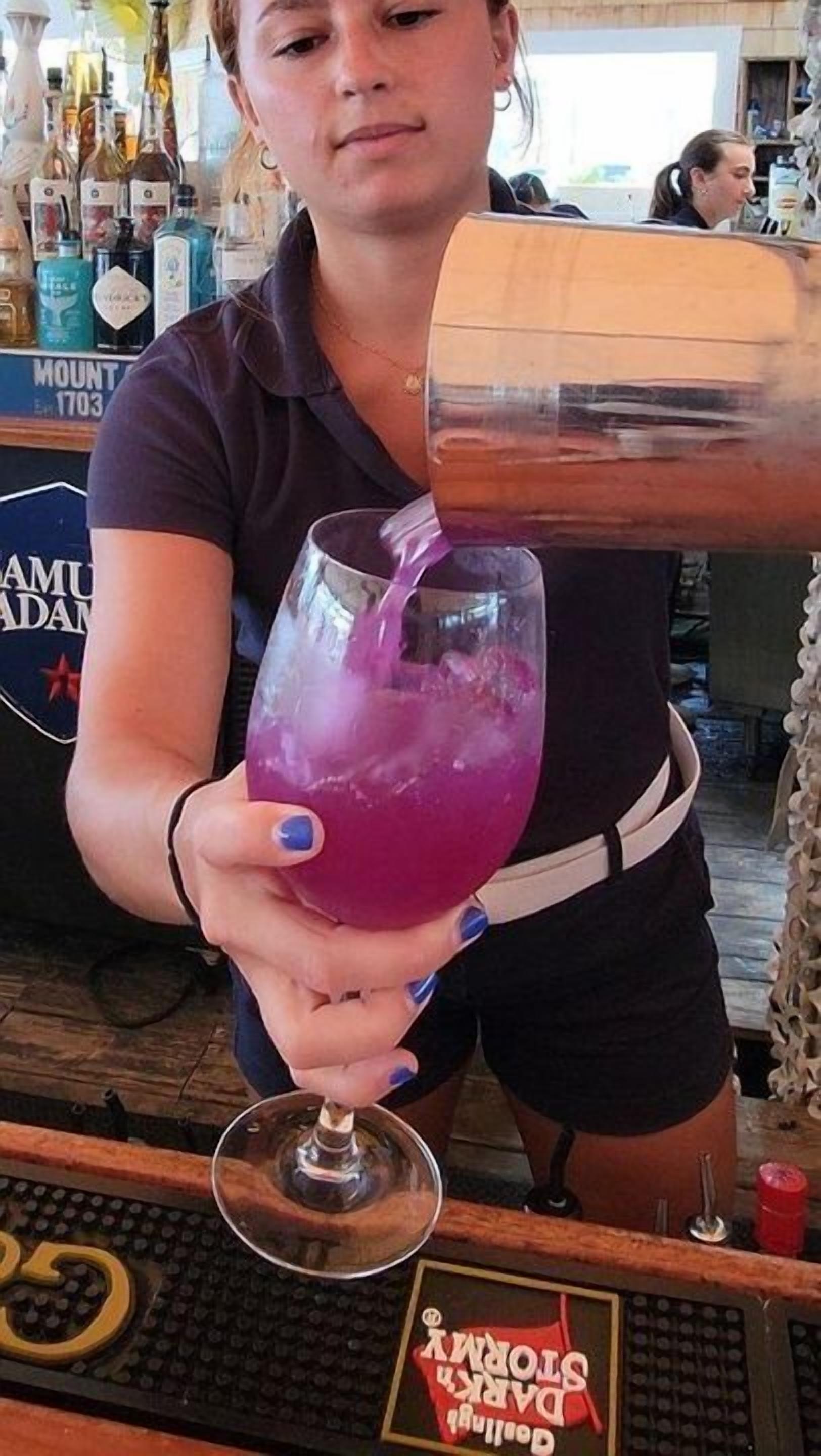 A bartender pouring a drink into a glass.