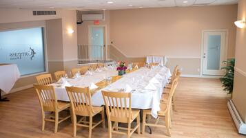 A conference room with a long table set for a meeting, wooden chairs, and a projector screen displaying a logo.