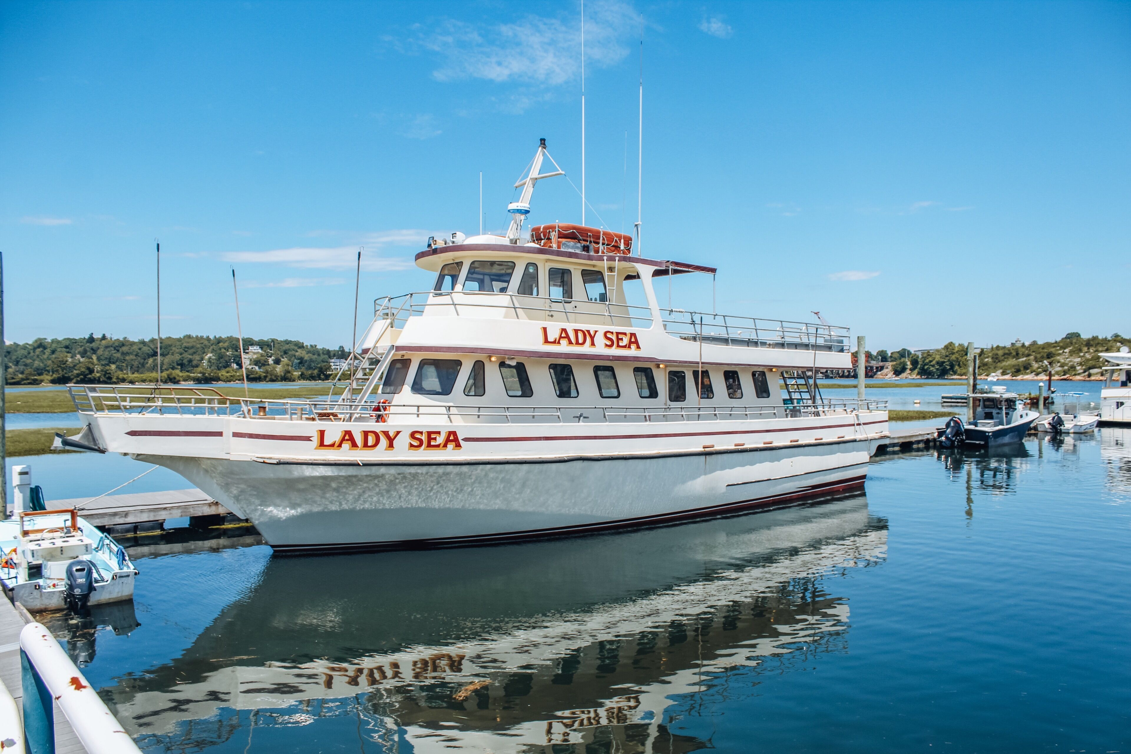 Un barco llamado "Lady Sea" amarrado en un puerto deportivo, con aguas tranquilas y cielo despejado.
