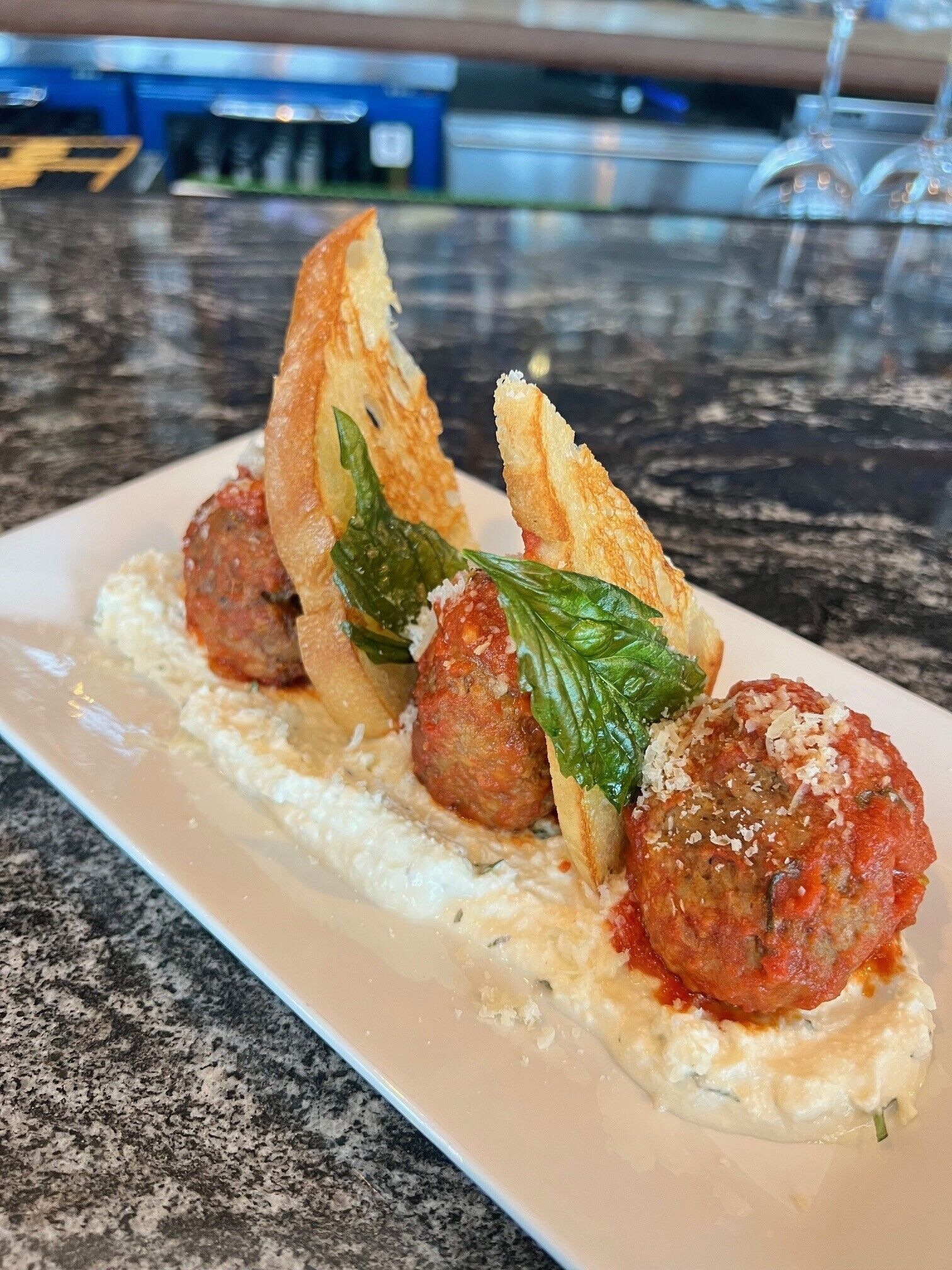 A plate with meatballs, bread, and a creamy sauce.