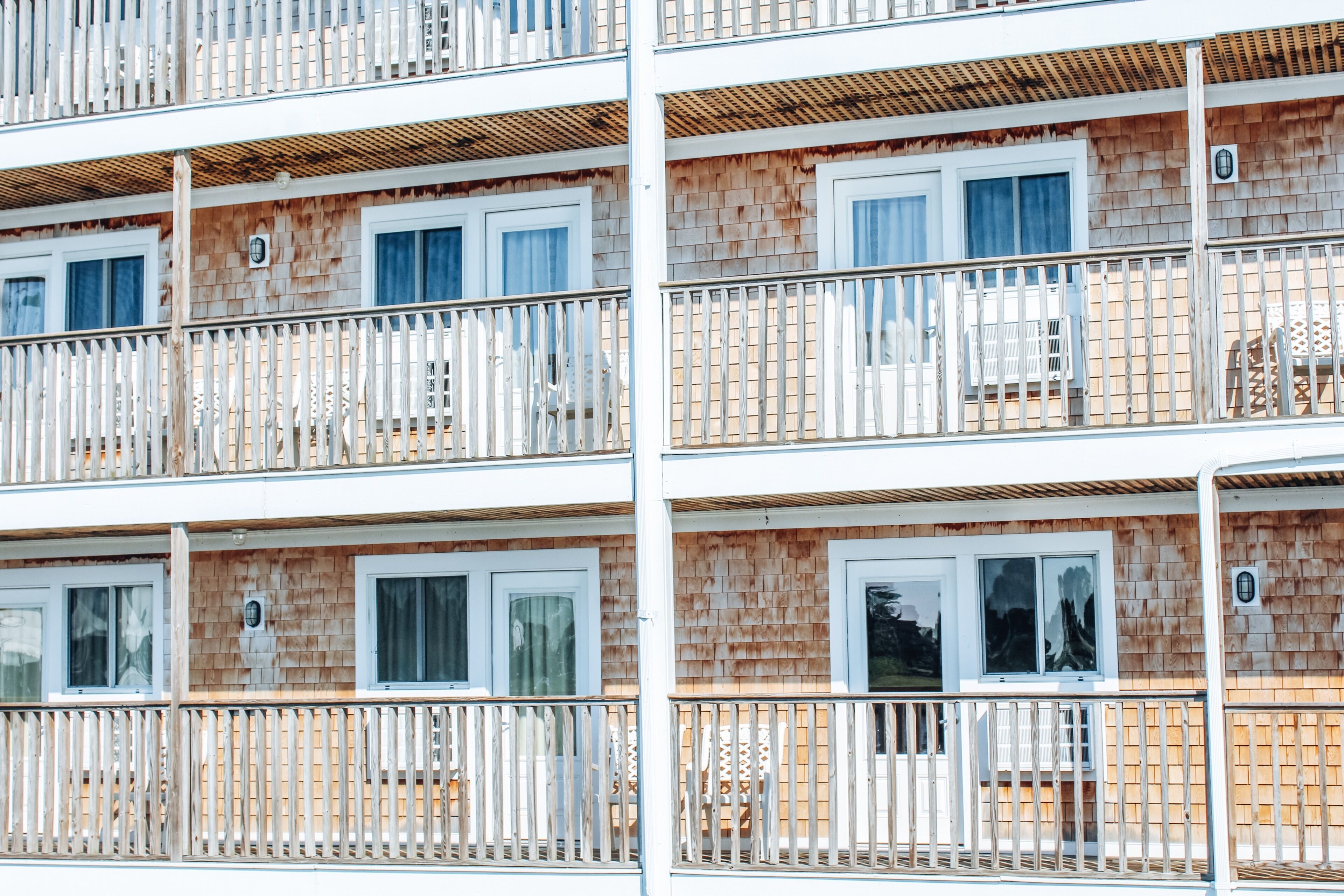 Un edificio de varios pisos con balcones, fachada de madera y barandillas blancas.