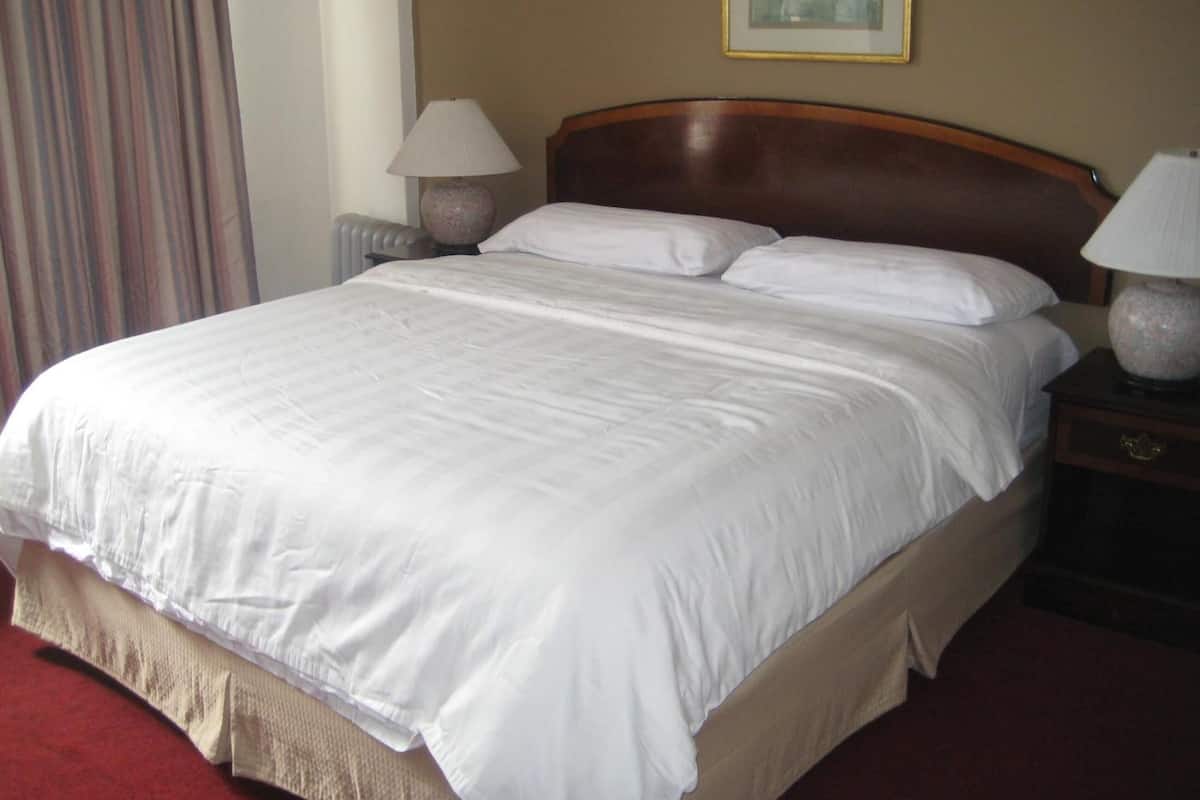 A neatly made bed with white linens in a hotel room.