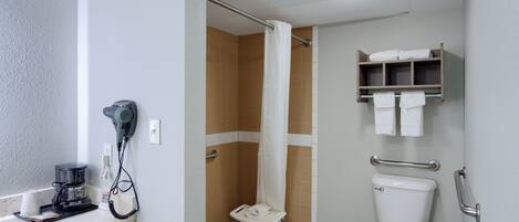 Ein Badezimmer mit Dusche, Toilette und Waschbecken, inklusive Kaffeemaschine.
