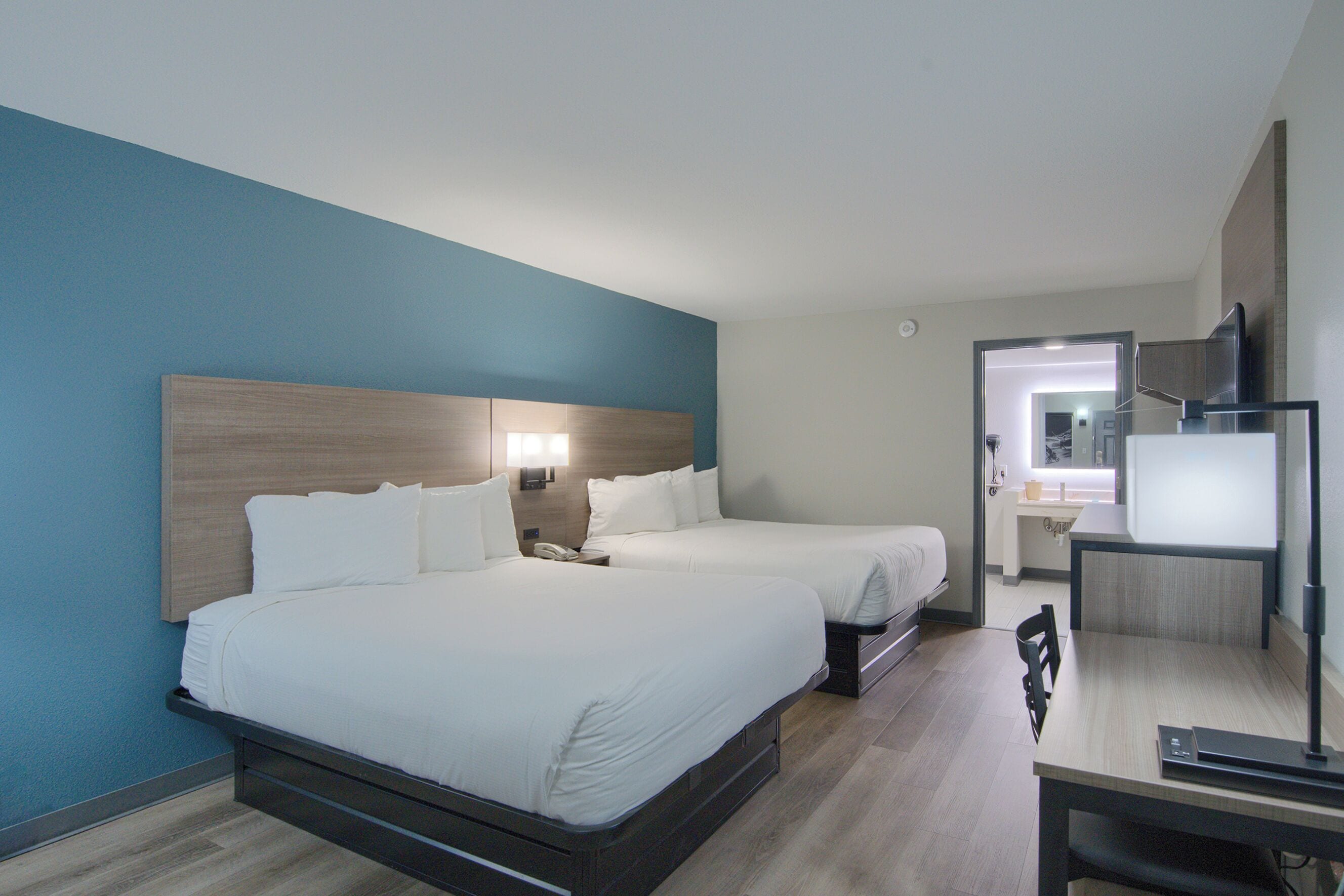 Une chambre d’hôtel avec deux lits, un bureau et une télévision.