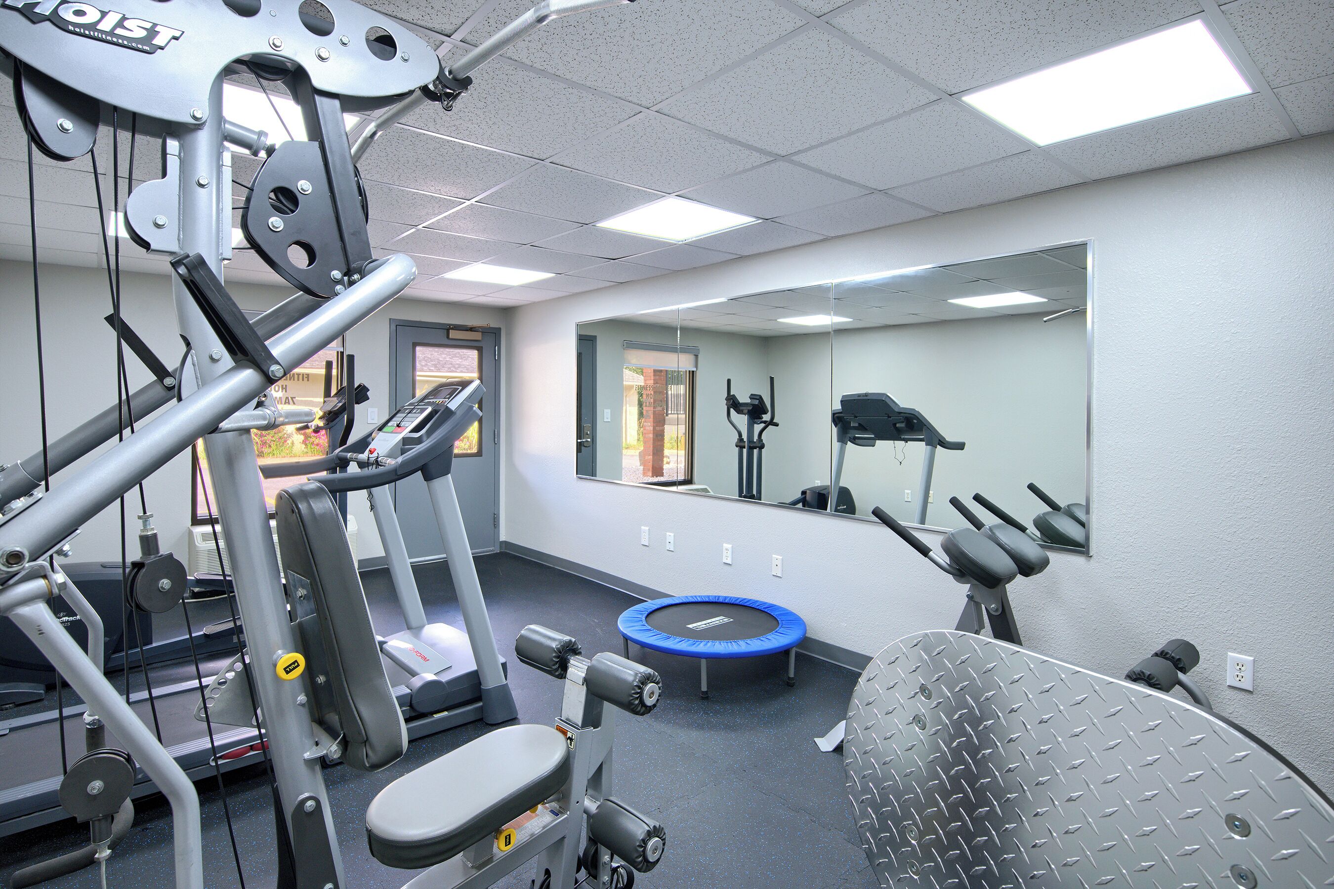 Une salle de sport équipée de matériel d’exercice, d’un miroir et d’un trampoline.