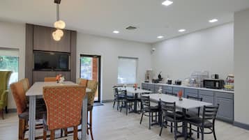 Una cocina moderna con comedor, que presenta una isla grande, electrodomésticos integrados y vistas al exterior.
