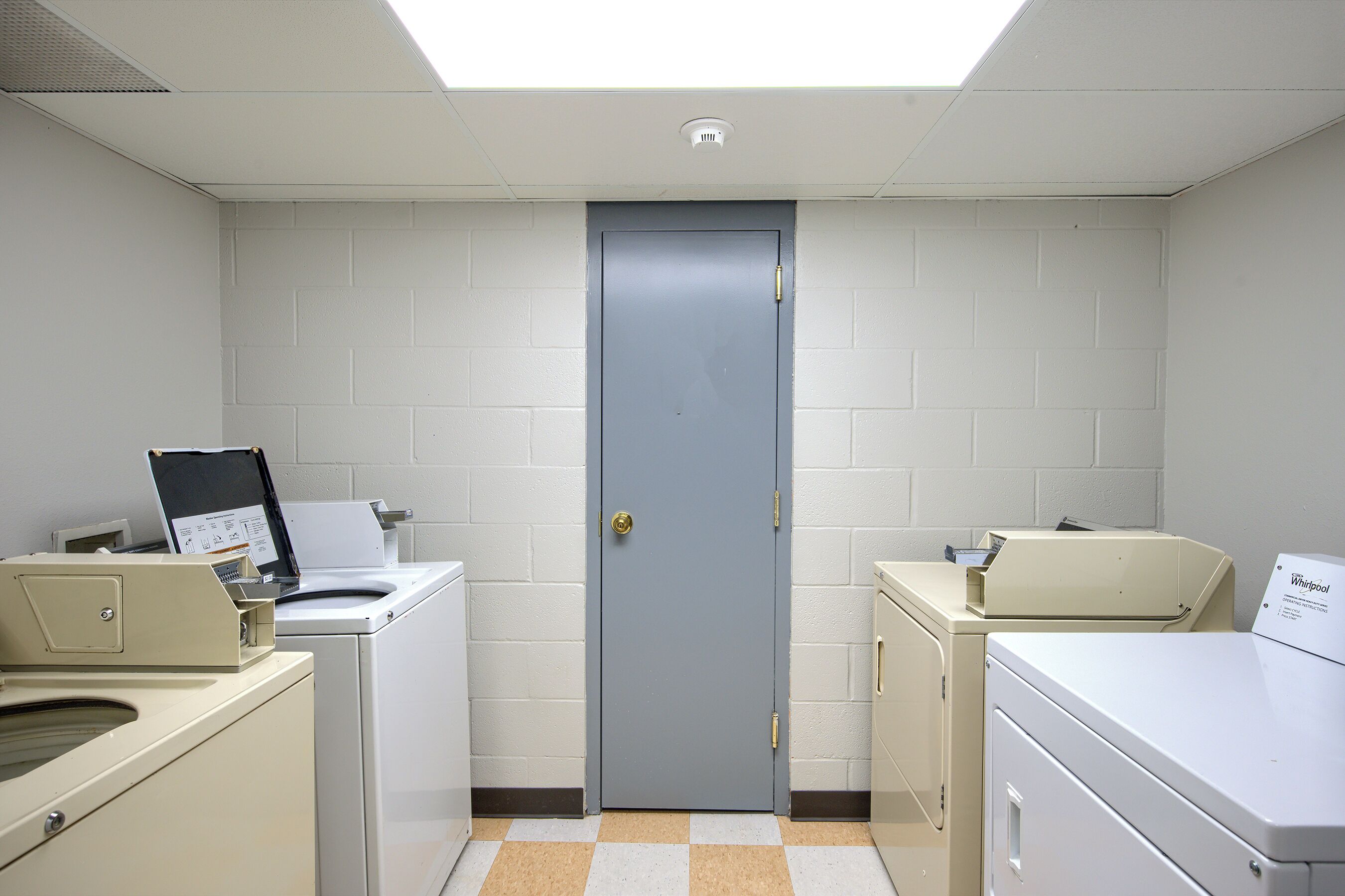 A laundry room with a door, washing machines, and a dryer.