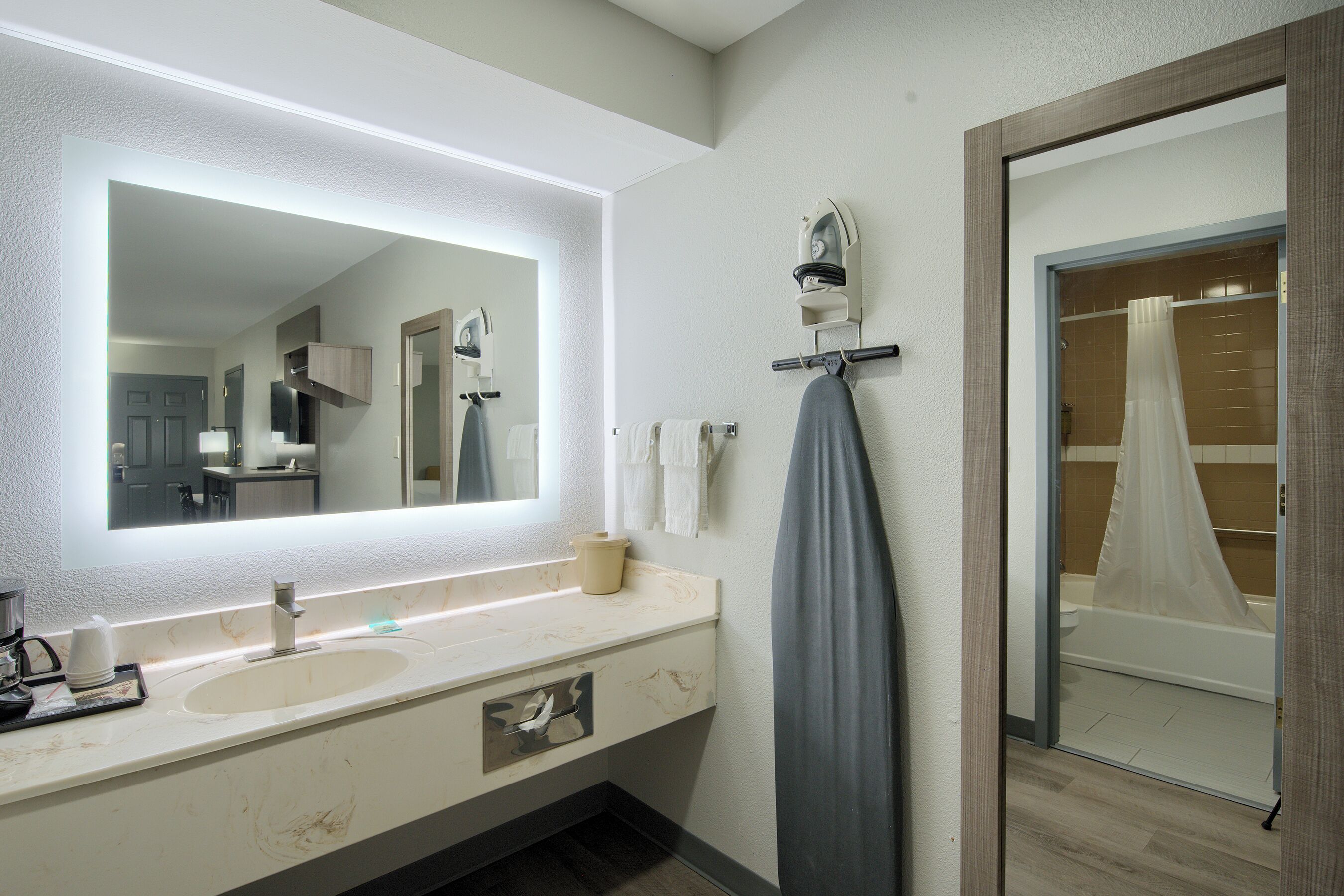 A bathroom with a large mirror, a sink, and a shower area.