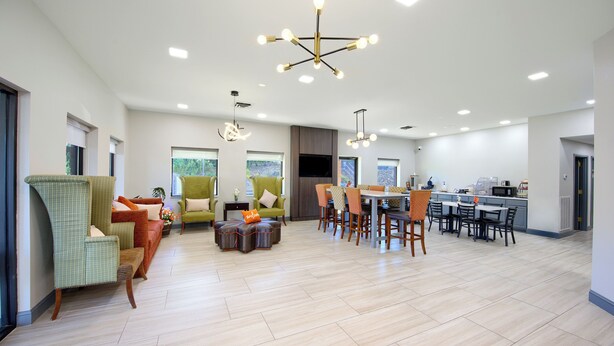 A spacious living area with a dining table, multiple chairs, and a kitchen in the background. - Hotsprings Village Inn (Hot Springs Village)