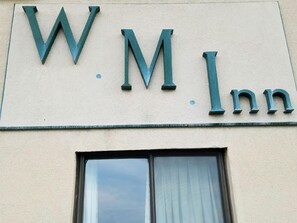 Une enseigne sur le bâtiment, avec les lettres « W.M. Inn », indiquant le nom de l’établissement.
