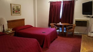 A hotel room with two beds, a small table with chairs, a TV, and a painting on the wall. - Woonsocket Motor Inn (Woonsocket)