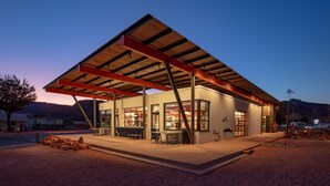 A modern building with a covered outdoor seating area, large windows, and a flat roof. - Best Friends Roadhouse and Mercantile (Kanab)