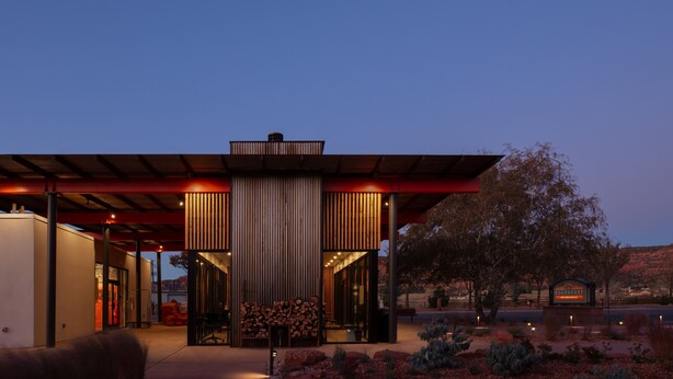 A modern building with a covered entrance, a stack of firewood, and a sign that reads "ROADHOUSE." - Best Friends Roadhouse and Mercantile (Kanab)