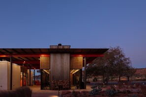 A modern building with a covered entrance, a stack of firewood, and a sign that reads "ROADHOUSE."