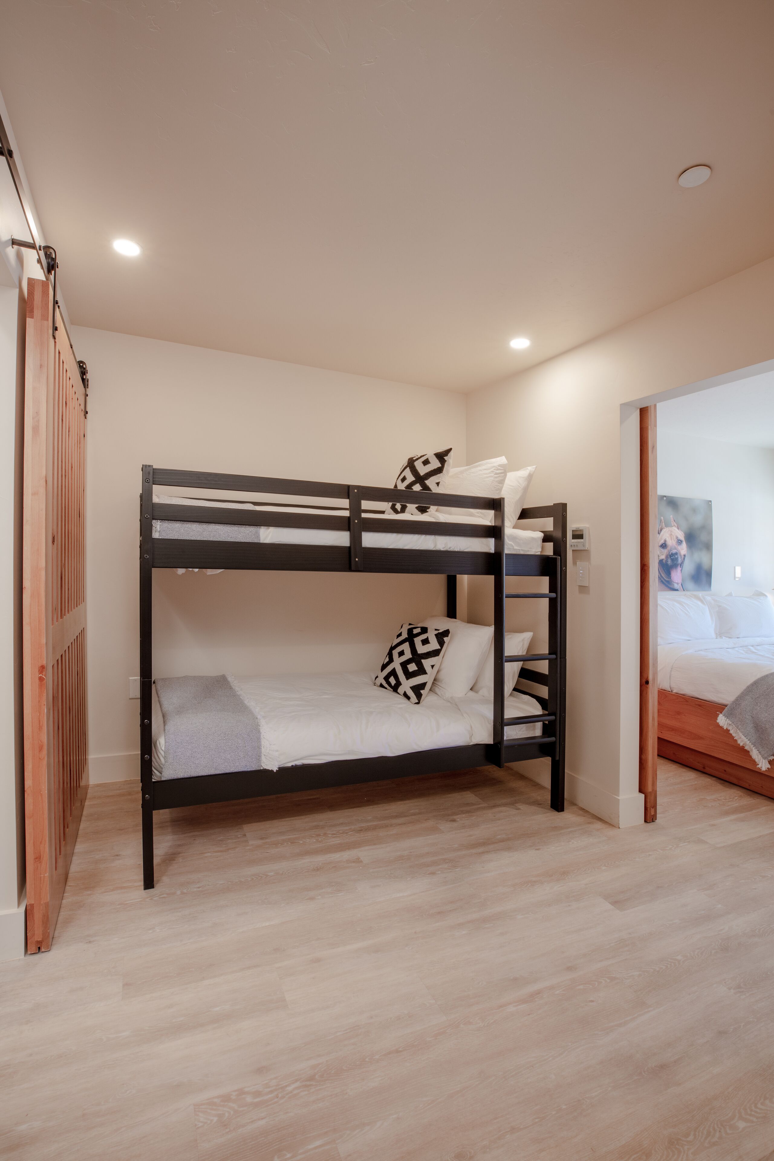 A bunk bed with a wooden frame, white bedding, and patterned pillows.