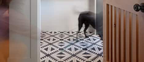 A hallway with a patterned floor, a round mirror on the wall, and a wooden door.