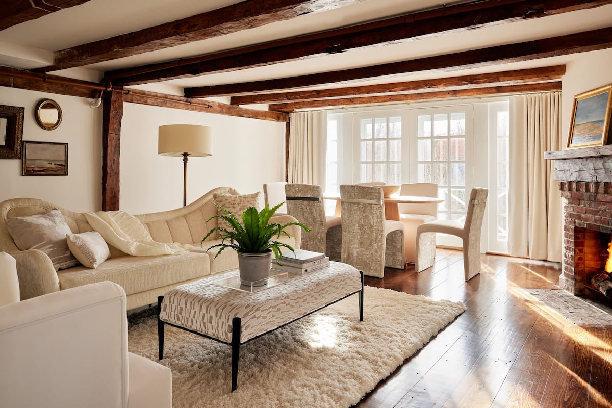 A cozy living room with a sofa, armchairs, a coffee table, and a fireplace.