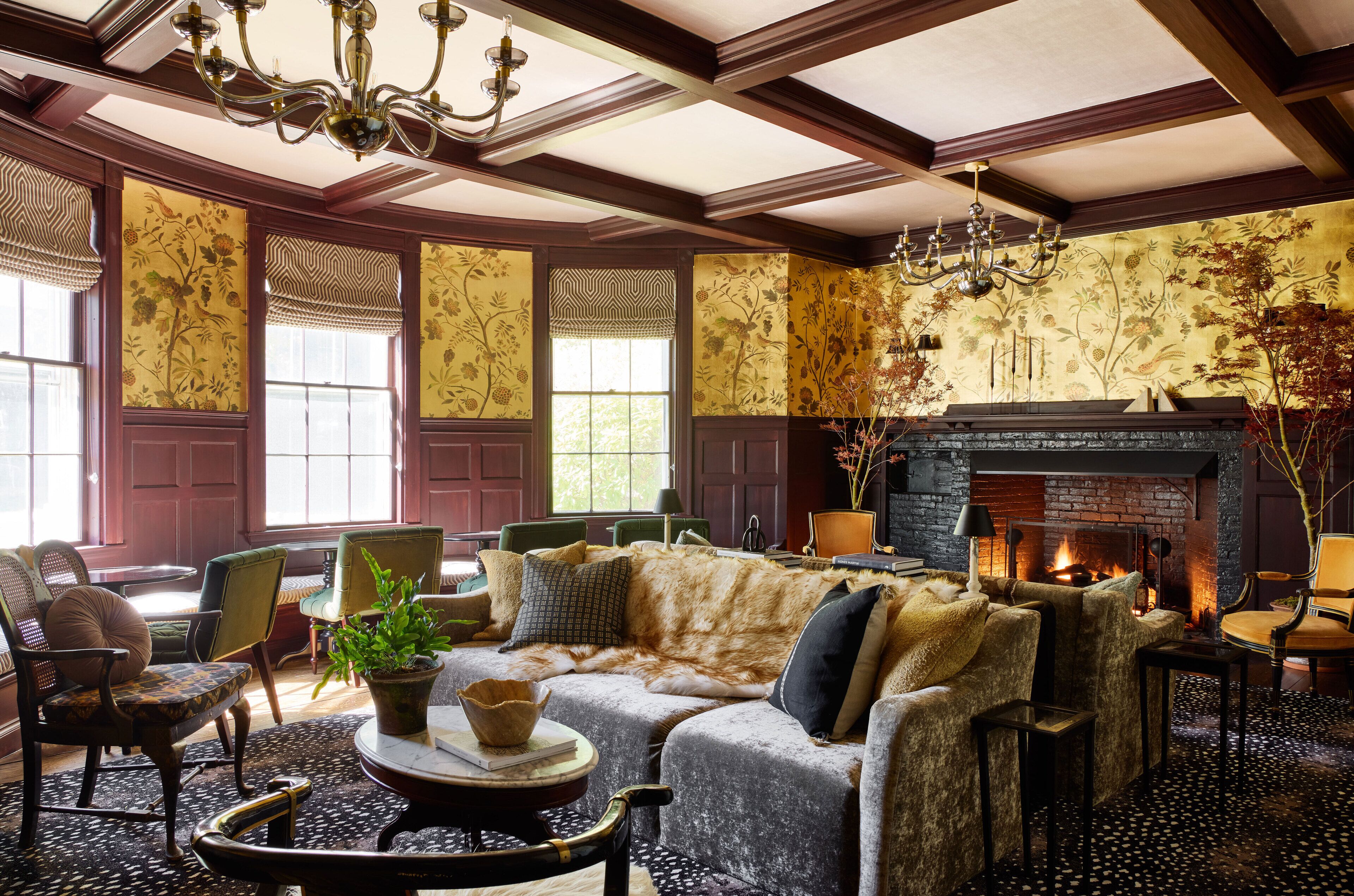 A cozy living room with a fireplace, comfortable seating, and decorative wallpaper.
