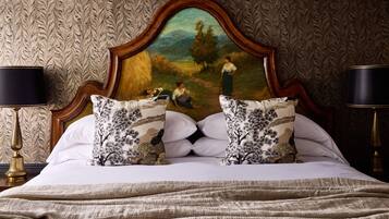 A bedroom with a large bed, two side tables, and a painting on the headboard.