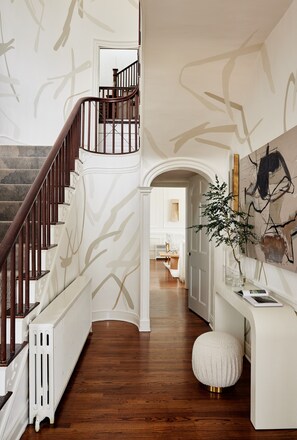 A staircase with a wooden handrail and white walls with abstract designs. - Kennebunkport Captains Collection (Kennebunkport)