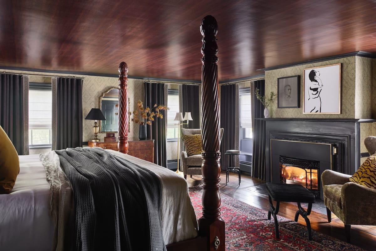 A traditional room with a four-poster bed, a fireplace, and a large mirror.