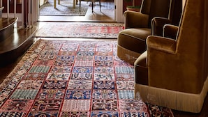 A spacious living room with a patterned rug, a chandelier, and a large plant. - Kennebunkport Captains Collection (Kennebunkport)