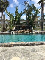 Una piscina al aire libre, sombrillas, sillones reclinables de piscina