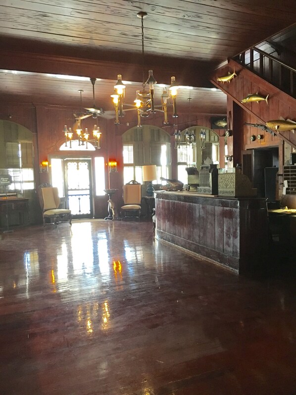 A spacious lobby with a polished wooden floor, a reception desk, and a staircase. - Rod And Gun Club (Everglades City)