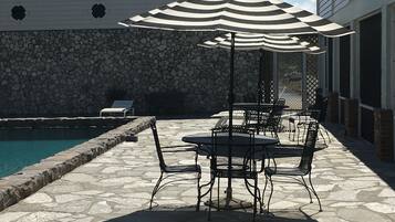 Un patio con suelo de piedra, mobiliario exterior y una piscina.