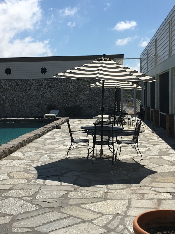 A patio area with stone flooring, outdoor furniture, and a pool.