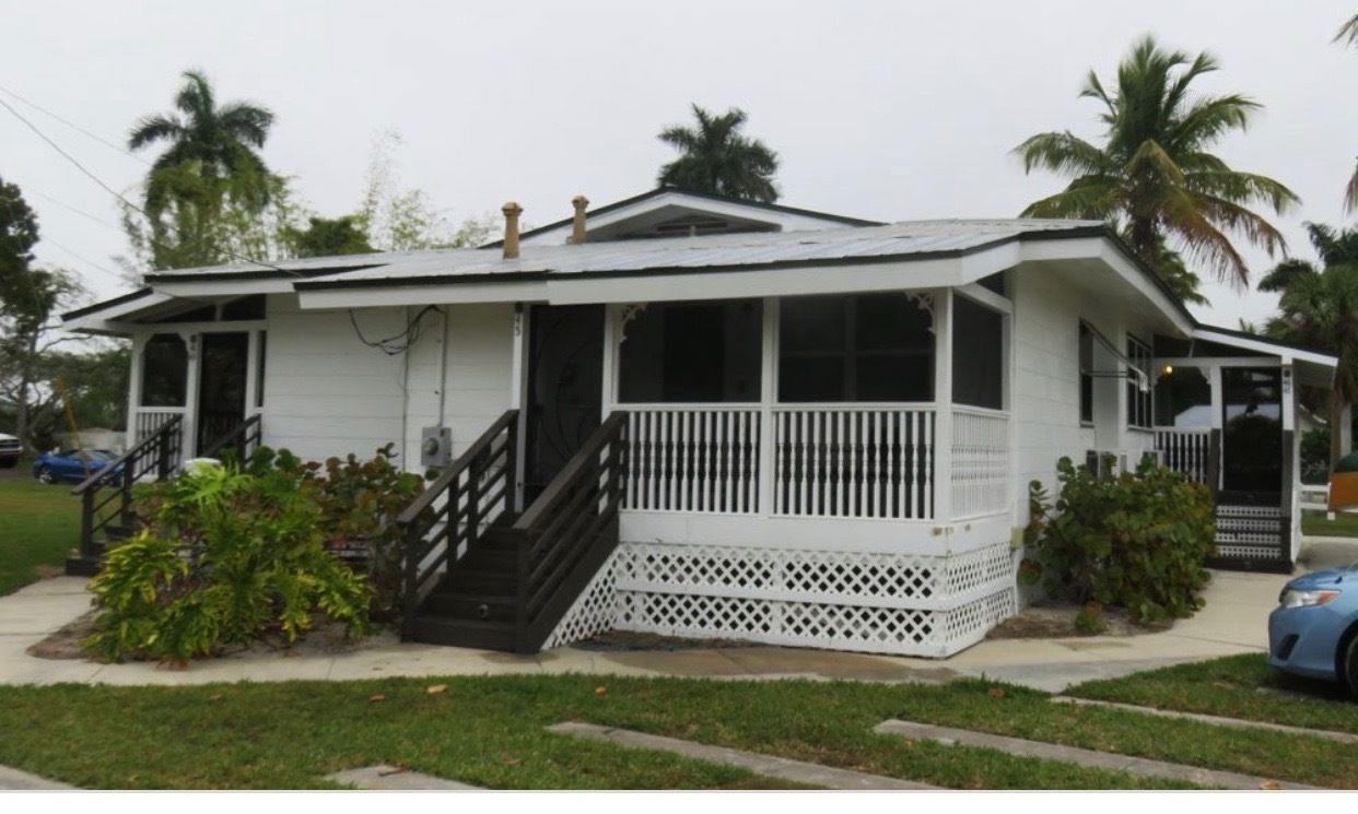 A single-story house with a porch, a staircase, and a small garden area.