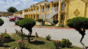 Un motel amarillo con varios balcones y una escalera central.