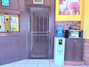 A door with a metal grill, a water dispenser, a microwave, and a cabinet. - Great Western Inn Pasadena (Pasadena)