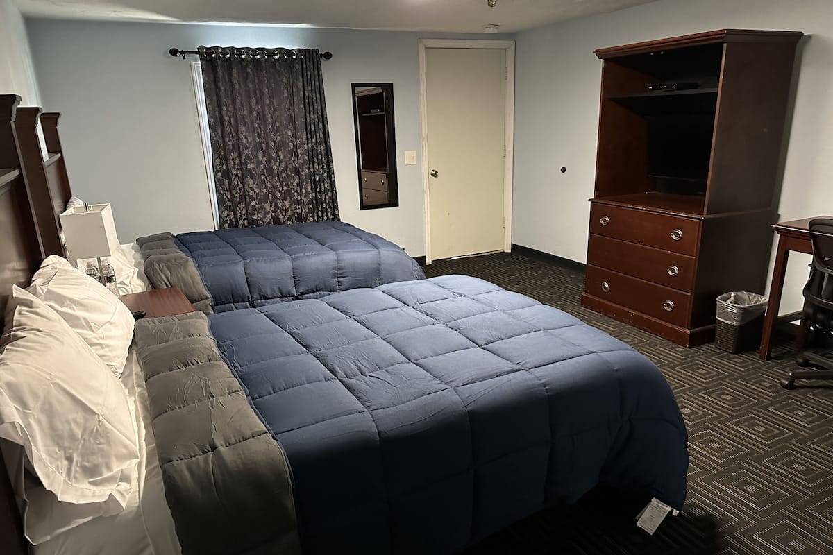 A hotel room with a bed, a dresser, a desk, and a television.