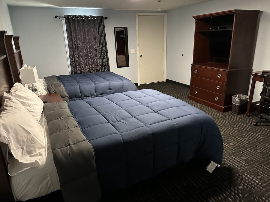 A hotel room with a bed, a dresser, a desk, and a television.