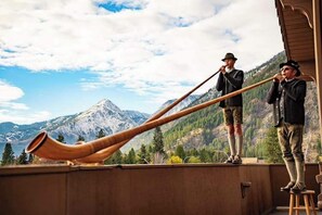 Two individuals on a rooftop with a large wooden pipe, a mountain backdrop, and a wooden structure. - Enzian Inn (Leavenworth)