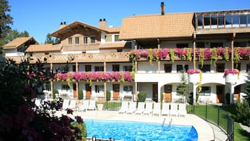 Relax by the pool surrounded by lush greenery and comfortable lounge chairs.
