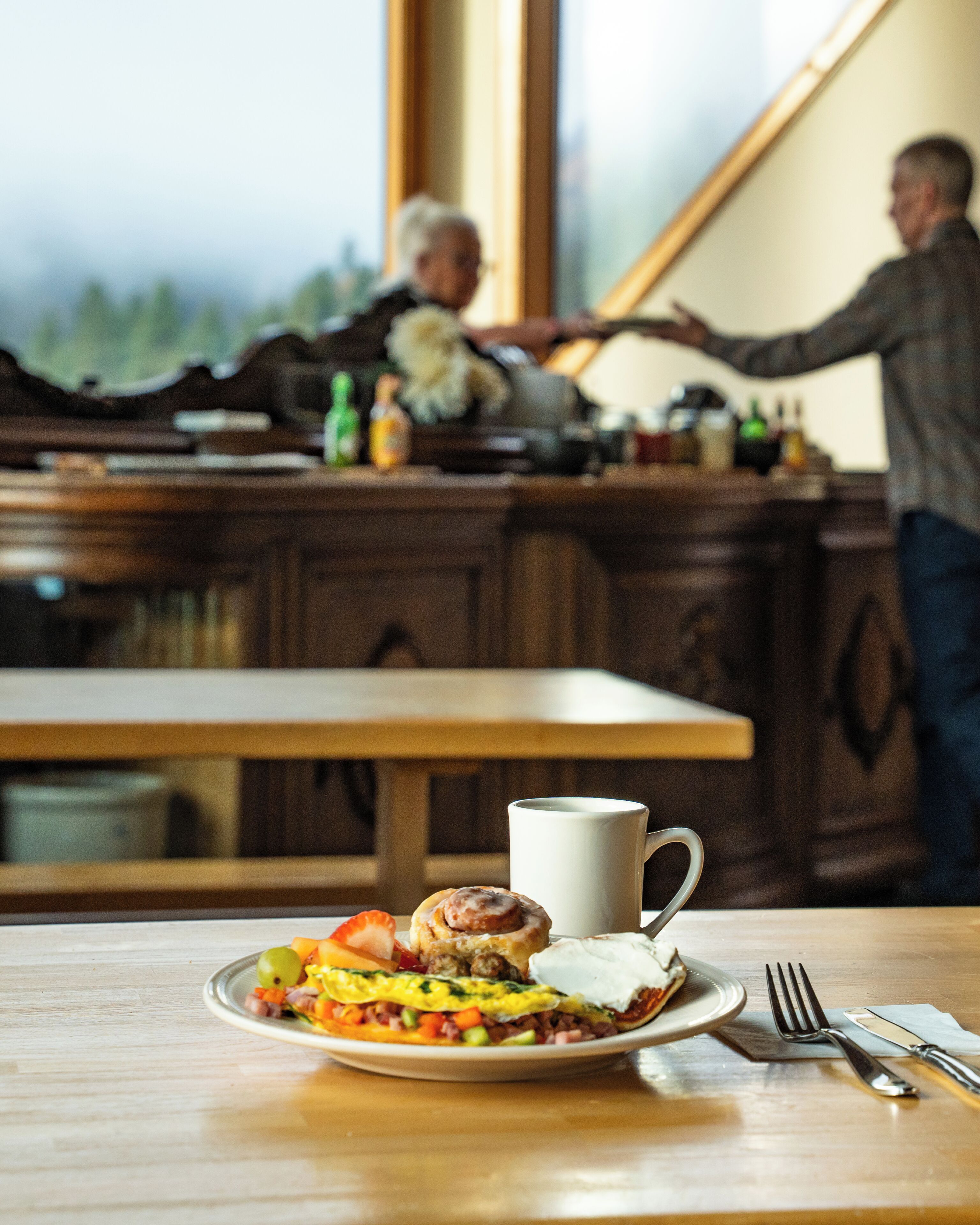 A breakfast table with a plate of food, a cup, and a fork.
