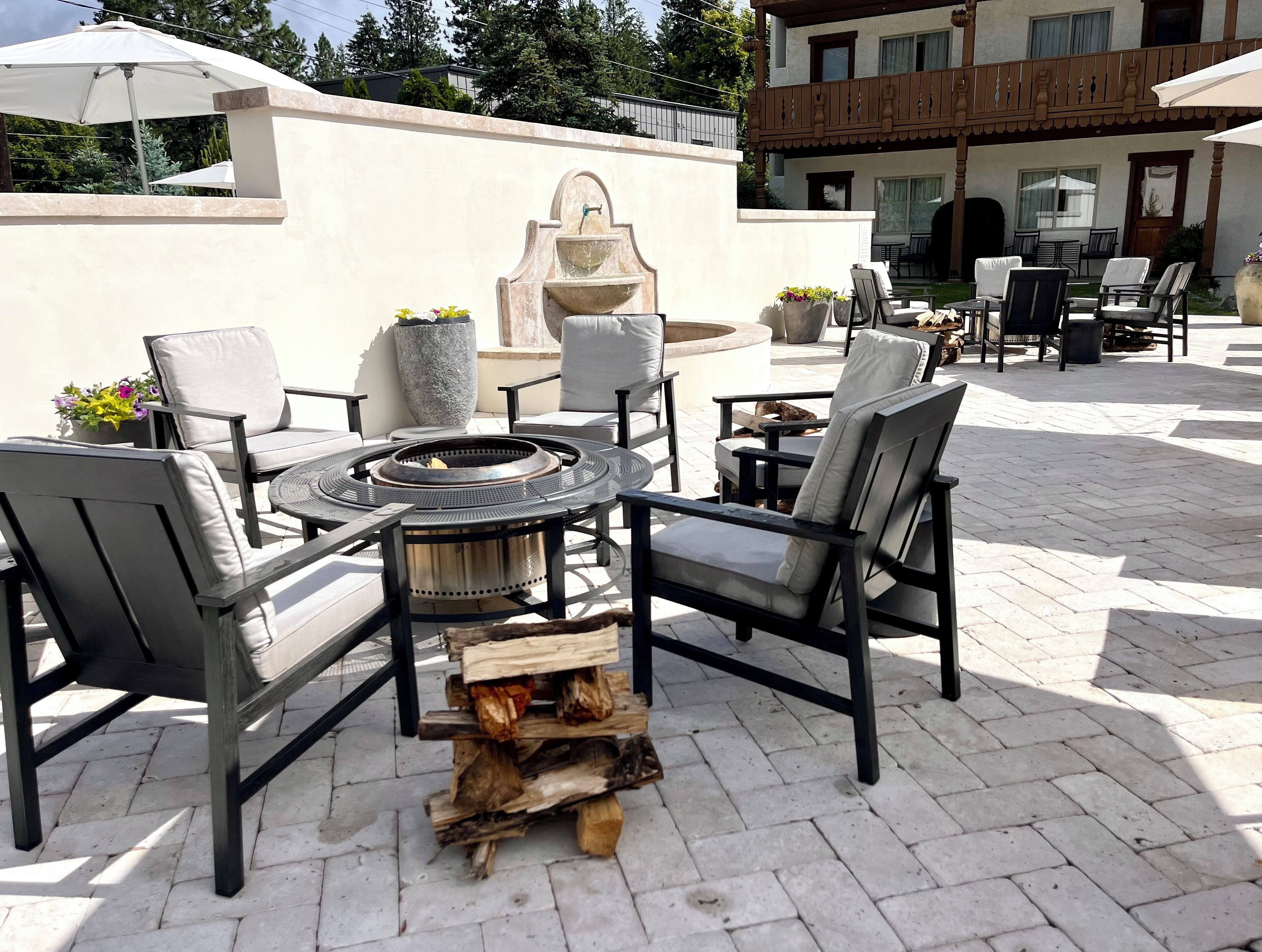 An outdoor patio with a fire pit, seating, and a fountain.