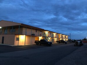 A motel with multiple rooms, a parking lot, and a few vehicles parked. - Royal inn (Borger)