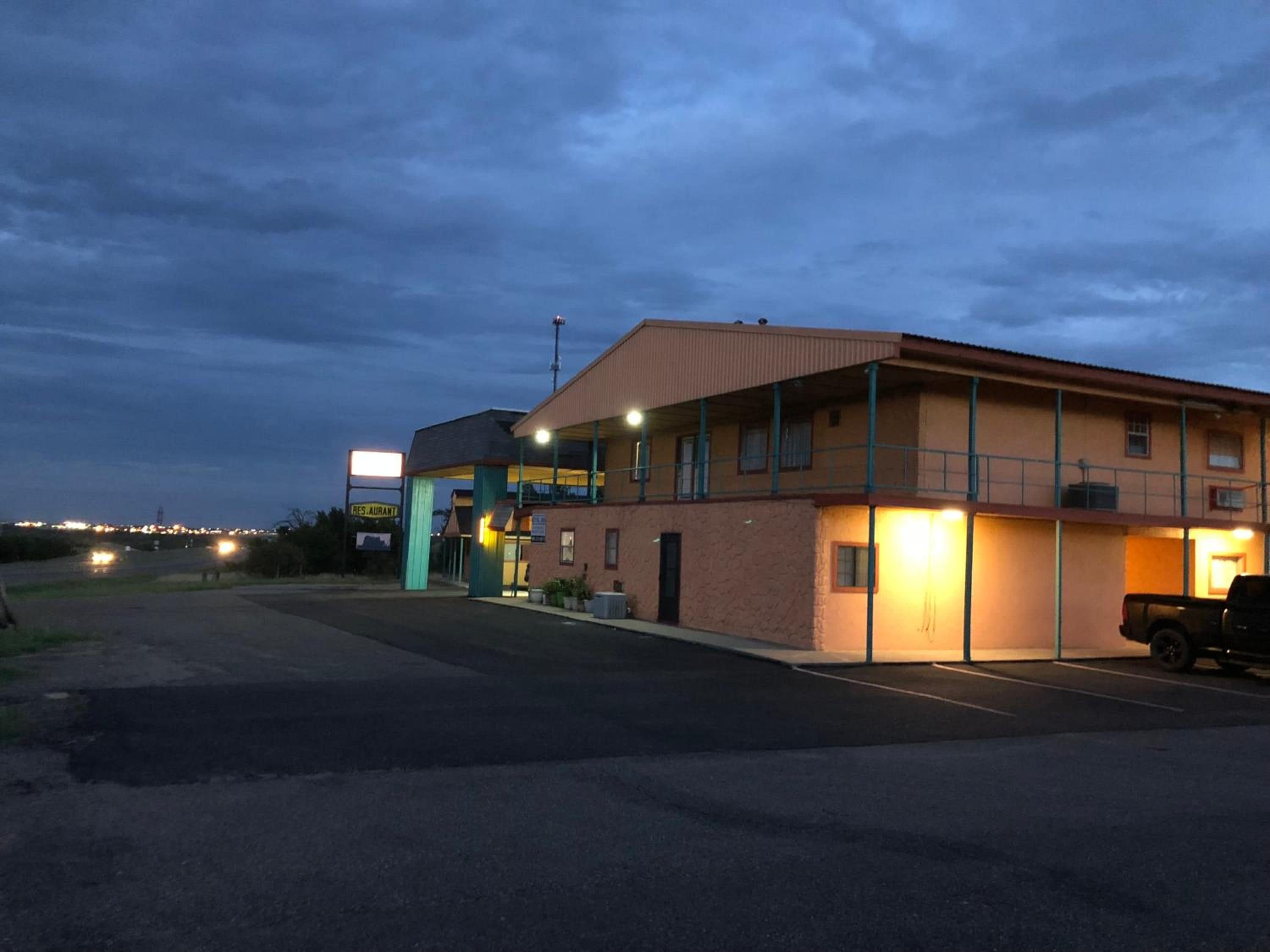 A two-story building with a flat roof and a parking lot in front.