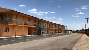 A motel with a two-story structure, a central staircase, and a parking lot.