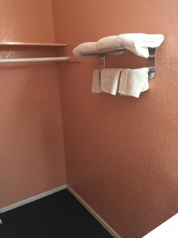 A bathroom with a towel rack holding two towels, a metal shelf, and a dark floor.