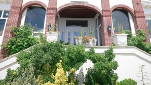 A Mayfair Hotel with a symmetrical facade, brick detailing, and a central entrance with a canopy. - Mayfair Hotel (Belmar)