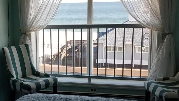 A room with a large window, a chair, and a bed. - Mayfair Hotel (Belmar)
