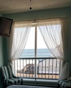 A room with a large window, a chair, and a bed. - Mayfair Hotel (Belmar)